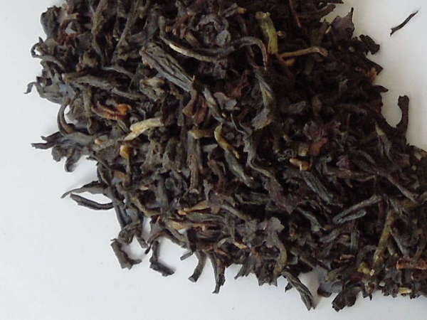 Loose-leaf black tea with mostly black and dark-brown colors, a few greenish-olive leaves