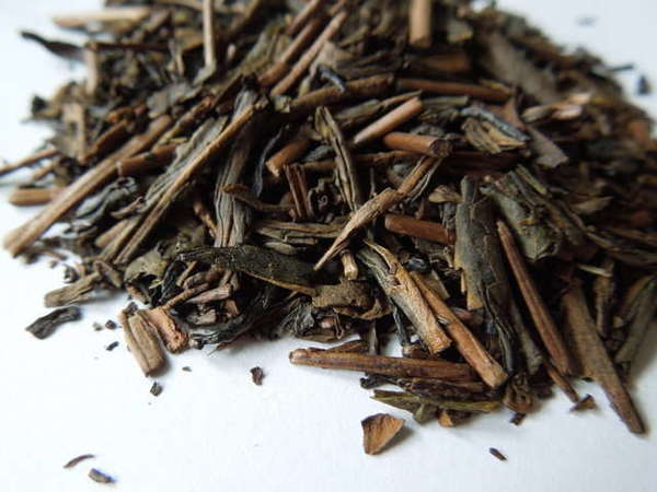 Long, flat, flakey, dark brown tea leaves with a wooden-looking color and texture