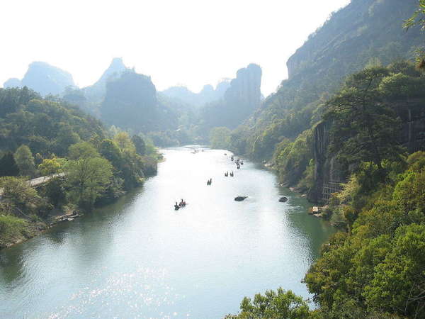 Broad river with very steep slopes, winding through craggy mountains with dense forest cover